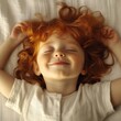 © StasySin - A young girl with red hair is sleeping on a bed. She is smiling and she is very happy