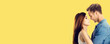 © vgstudio - Smiling happy cute couple. Profile portrait of stand close and look at each other man woman in love studio concept, isolate yellow background with free ad text space. Wide banner image