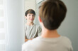 © AntonioDiaz - Confident teenager looking at his reflection in bedroom mirror