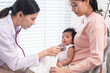 © Rakchanok - Caucasian pediatric doctor with mother and newborn during infant healthcare visit, medical consultation using stethoscope, representing professional examination, family support, child vaccination