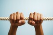 © Who is Danny - Close-up of two strong hands gripping a thick rope with determination against a soft light blue background symbolizing strength and perseverance. Ai generative