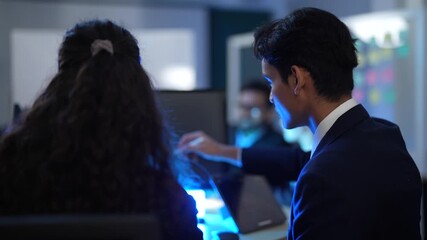 A diverse team of IT professionals brainstorms in a strategy meeting. A male developer presents a new app design on a tablet to his smiling and engaged colleagues.