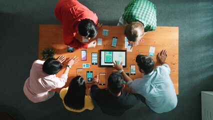 Top view of software developer team looking Ux Ui design for mobile phone interface from tablet while comparing and planning wireframe prototype designing together at creative workplace. Convocation.