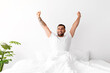 © Prostock-studio - Glad cheerful energetic millennial muscular european male wakes up, stretches body on bed in bedroom interior, empty space. Guy enjoy good morning, free time, weekend and vacation, vitality at home