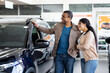 © Anastasiya - Young African American couple smiling while discussing new SUV inside dealership showroom, lifestyle and transport concept of auto sales, business and finance decision.