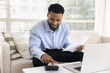 © fizkes - Busy smiling young man using calculator to do budgeting work
