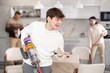 © JackF - Guy vacuuming floor while his relatives help tidy up the room