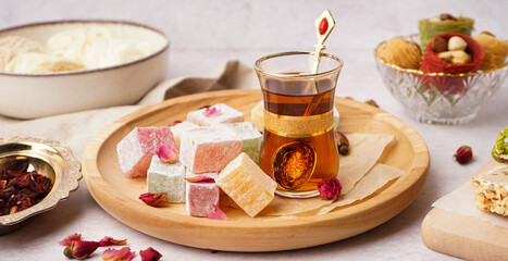 Wall Mural - Plate with tasty Turkish Delight and glass of tea on light background
