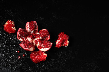 Wall Mural - pieces of delicious ripe pomegranate on black background
