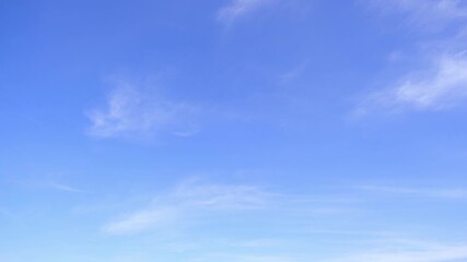 Wall Mural - a timelapse reveals a calm blue sky with faint streaks of white clouds drifting softly, symbolizing 