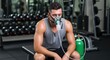 © Dara - A man wearing a mask and sitting on a bench in a gym.