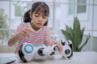© FAMILY STOCK - Asian girl repairing toy robot with screwdriver, learning STEM education and robotics engineering. Concept of child creativity, innovation, future technology skills and digital learning.