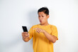 © Ichsan Gallery - Smiling Young Asian Man In Yellow Shirt Using Smartphone Pointing at Device on White Background