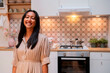 © Westend61 - Smiling woman standing in modern kitchen looking at camera