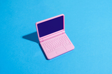 Pink laptop on blue background with copy space in studio