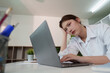 © itchaznong - Stressed young woman working on laptop in modern office