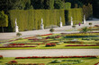 © Travel 'n' Lifestyle - View of vibrant flower beds and statues lining the manicured gardens under the summer sun, a jogger enjoying the scenery, SchÃ¶nbrunn Palace, Wien, Austria.