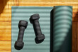 © Tetra Images - Overhead view of partially rolled yoga mat and weights on wooden floor