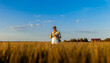 © Zoran Zeremski - Confident farmer standing in wheat field at sunset examining crop in his hands.