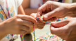 © Aurora Aesthetics - Children's hands making colorful friendship bracelets at a charity summer camp