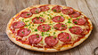 © AliRza - A round, classic pepperoni pizza sits on a rustic wooden table. The pizza has a thick, golden crust and is topped with bright red pepperoni slices and melted cheese, with a sprinkle of fresh parsley.