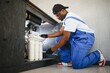 © Serhii - African american plumber change the water filter.