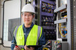 © JD Studio - Engineer conducts thorough inspection of powerplant control panel ensuring safety and efficiency. Wearing hard hat and safety vest, they use tablet and radio for communication