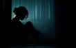 © Doyok - Silhouette of a woman sitting alone in a dimly lit room