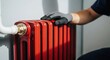 © Megin Design - Man touching radiator red. Radiator red is an essential component for home heating, with pipe, valve, and safety gloves visible.