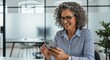© IPutuToya - Smiling Mature Businesswoman Using Smartphone in Modern Office
