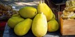 © Artem - Pile of fresh jackfruit on display at a tropical market for sale.