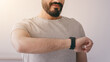 © Prostock-studio - Cardio workout at home, covid-19, exercise result and active sport. Handsome young 30s bearded arabian man checks pulse on fitness tracker and holds bottle of water in bedroom interior, copy space