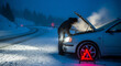 © Suraaj - Car breakdown on snowy mountain road at night with driver checking engine, warning triangle and headlights in cold winter foggy conditions