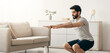© Prostock-studio - Online workout at home with modern device, be safety during lockdown. Serious arabian bearded millennial man squats in living room interior, looks at laptop on floor, near bottle of water, free space
