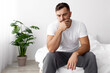 © Prostock-studio - Unhappy sad millennial european muscular male sits on white bed and suffers from stress and thinks in bedroom interior. Problem solution, depression, self isolation, weakness during covid-19 pandemic