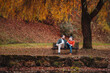 © Halfpoint - Son and older father sitting on bench by lake and talking.