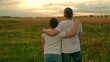 © Victoriia - Child son hugs dad on sunny meadow. Boy child hugs dad outdoors. Father loves his son, happy hugs dad child on lawn. Family walk nature. Family, dad son walk together in sunny park. Parent son, picnic
