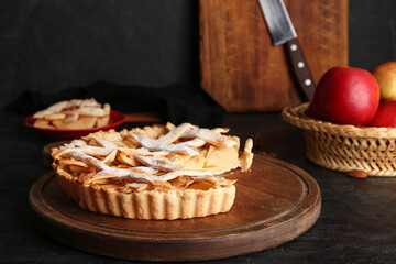 Wall Mural - Wooden board with delicious apple pie on black background