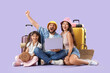 © Pixel-Shot - Family of tourists with laptop and suitcases sitting on lilac background