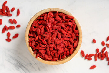 Wall Mural - Wooden bowl with red dried goji berries on white background