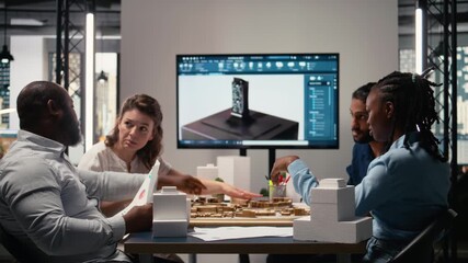 Engineers and real estate developers reviewing smart city design layout on architectural 3D models, brainstorming ideas for modern infrastructure, innovation and residential housing. Camera A.
