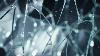 Abstract macro shot of shattered glass with intricate crack patterns and light reflecting off the sharp edges.