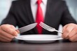 © Elena - Man in suit holding knife and fork over an empty white plate. Waiting for meal concept, business lunch advertising or restaurant service.