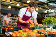 © JackF - Young male seller in apron takes tomatoes from window. Concept of proper nutrition,healthy lifestyle