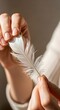 © Helmalia - Delicate white feather held gently by two hands, symbolizing lightness, fragility, and nature's beauty.