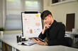 © Prathankarnpap - Businessman in black suit working on digital tablet with financial charts in background
