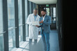 © Westend61 - Doctor and businessman discussing work on notebook in office corridor