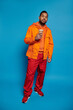 © LIGHTFIELD STUDIOS - Vibrant young man in urban fashion poses confidently in stylish orange attire