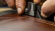 © Metthaisonk - Close-up of skilled hands sewing leather with precision tool in a craftsmanship setting.