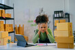 © Parichat - Stressed african american woman entrepreneur holding head in hands at her store